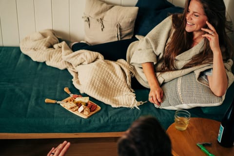 Woman laughing on a green daybed with a cheese board and a glass of white wine