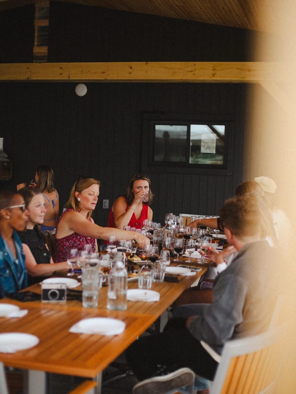 Guests share a long table of wine glasses and snack plates during a Vico Vino Van tasting