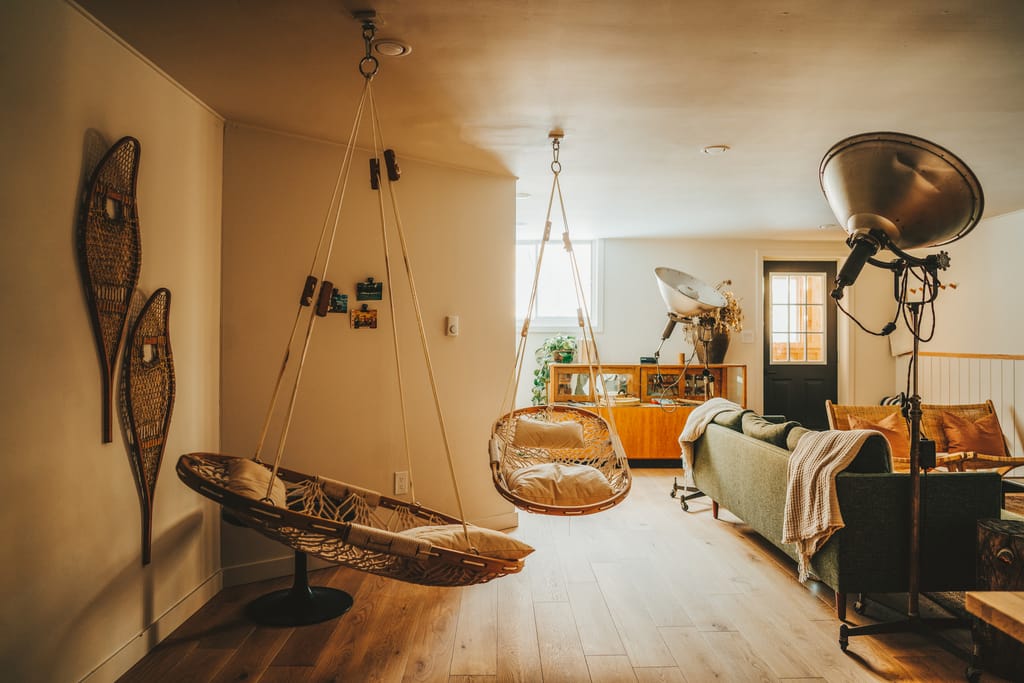 Living room with two hanging rattan chairs, snowshoes on the wall and a green sofa