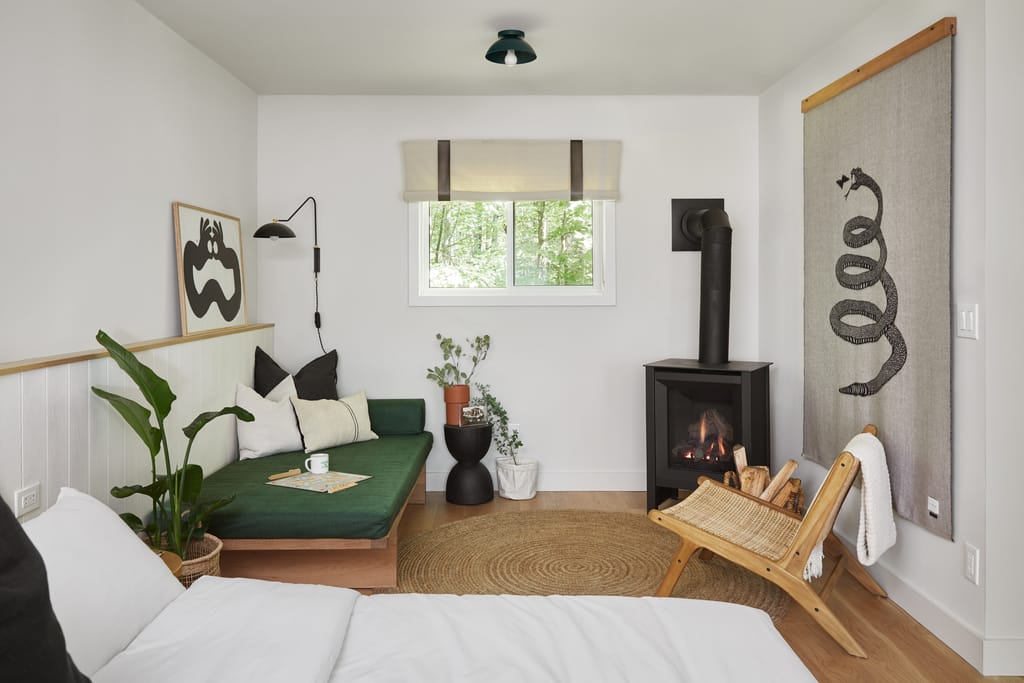 Guest room with a green daybed, gas stove, rattan chair and woven rug