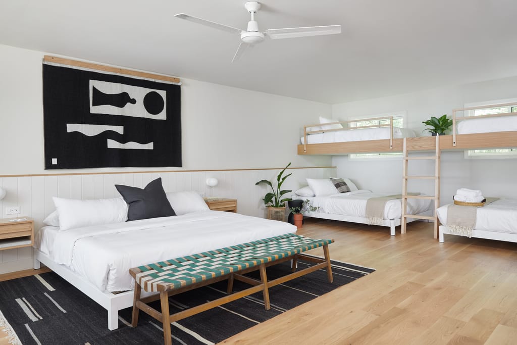Large family room with a king bed, a bunk bed with ladder and a woven bench