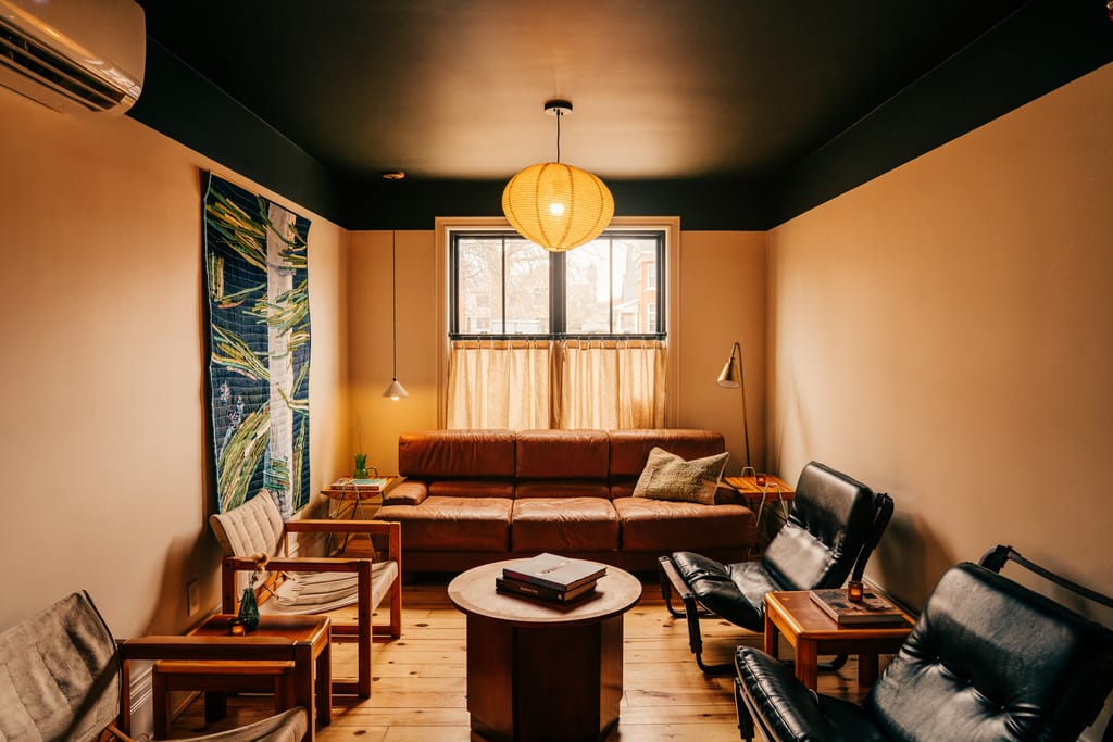 Sitting room with a leather sofa, black armchairs and a round table under a paper lantern