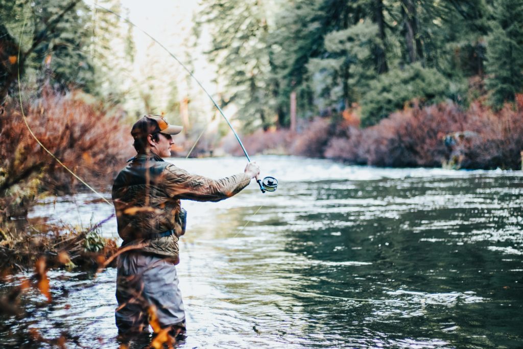 Credit: Greysen Johnson. Fly fishing on a river surrounded by trees