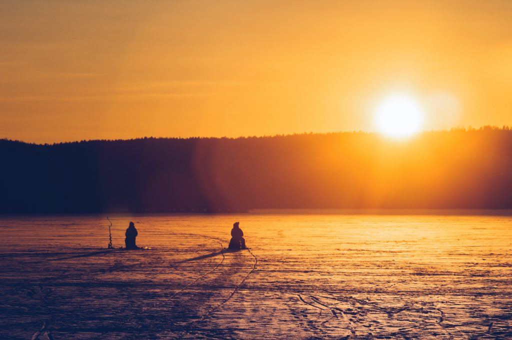 Credit: Herts Niks. Ice Fishing on a snow covered lake during sunset